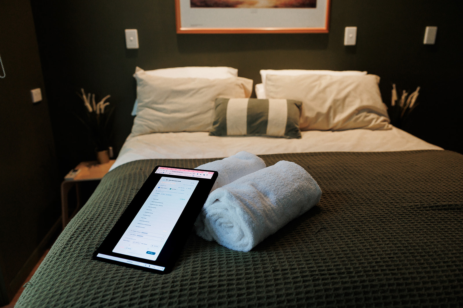 A cleaner's tablet showing the Room Hub checklist on a freshly made bed